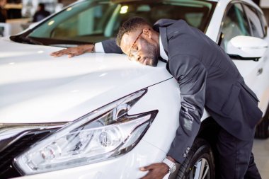 Yakışıklı siyah adam yeni arabasını sarılma ve gülümseyen