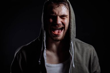 Öfkeli ve saldırgan erkek, yeşil hookie bağırarak ve kameraya bakıyor