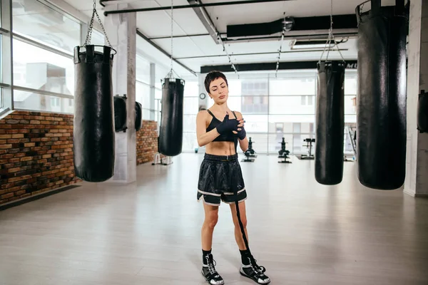 Mujer en pantalones cortos de gimnasio y camisa con vendaje de boxeo en el gimnasio. envolver la mano lesionada . — Foto de Stock