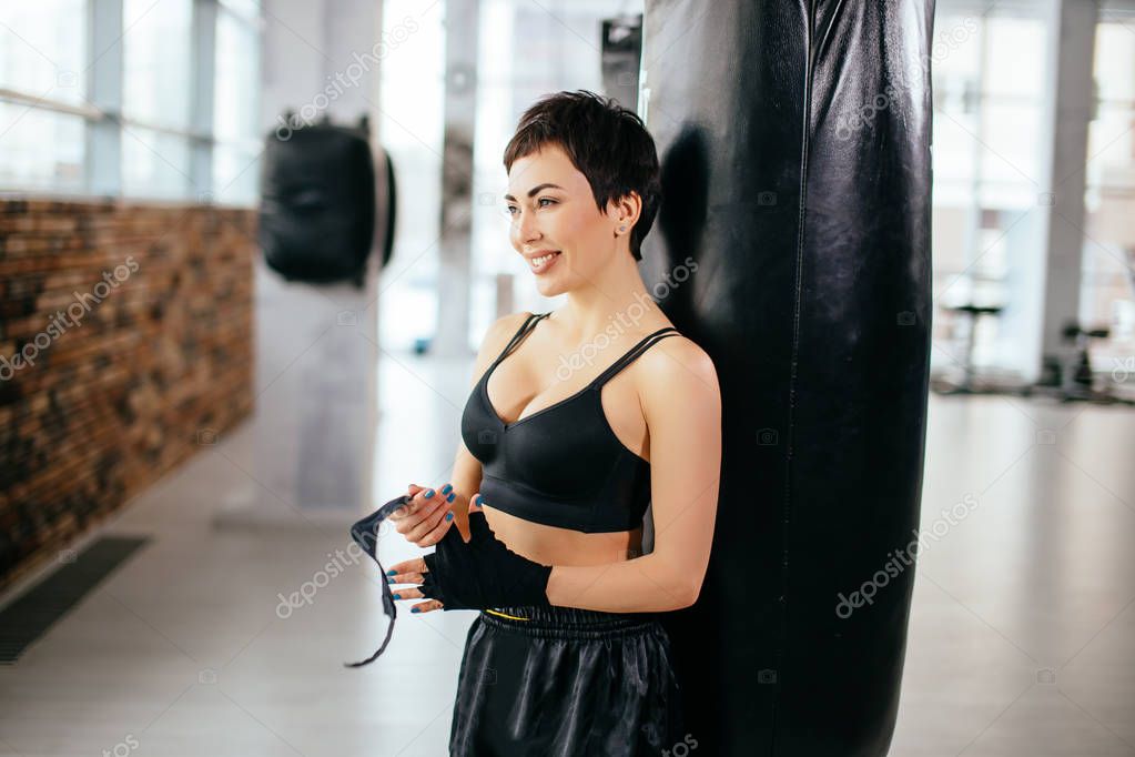 side view shot of smiling athlete wrapping black bandage on hands