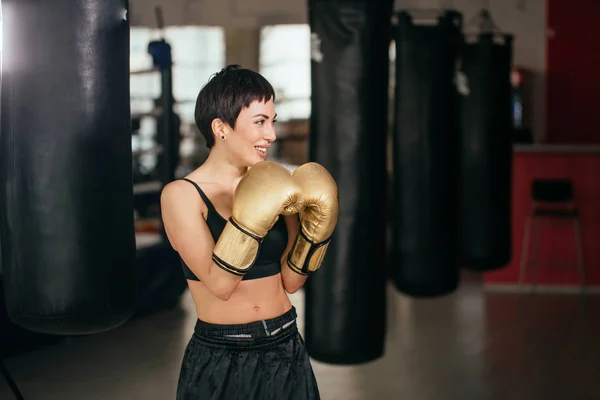 Mujer sonriente en traje deportivo negro mostrando golpe de boxeo —  Fotos de Stock