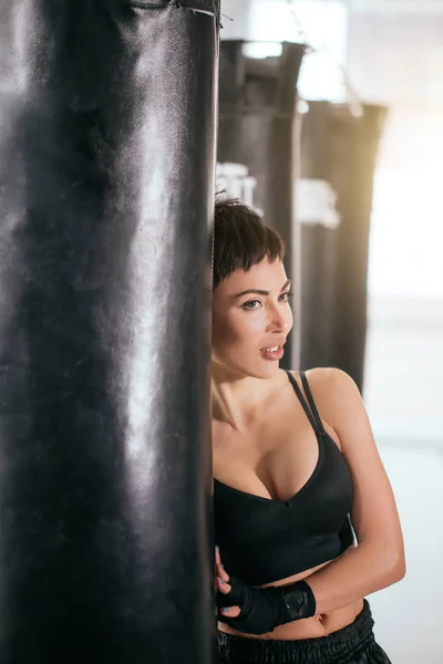 pretty sexy woman standing behind the boxing bag with dreaming happy look