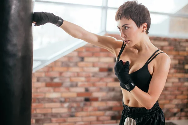 Joven boxeador tailandés guapo practicando con bolsa de boxeo en clase de boxeo — Foto de Stock