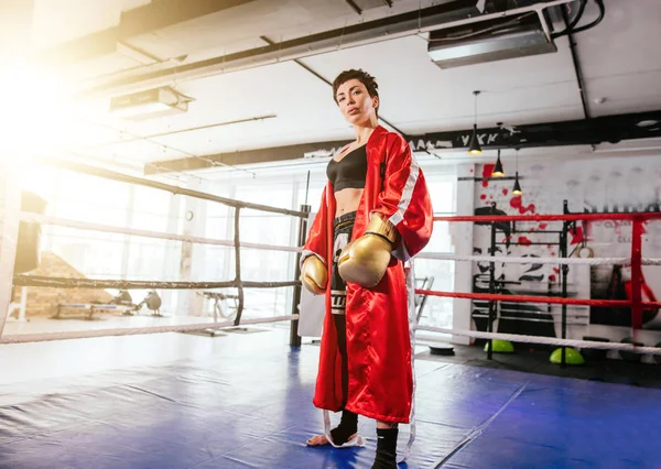 Formidable wonan en equipo deportivo para el boxeo mirando a la cámara en el ring en el gimnasio — Foto de Stock