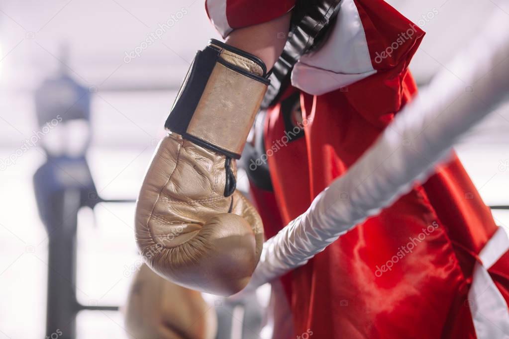 side view shot of sportswoman in red sportswear hanging her yellow boxing gloves
