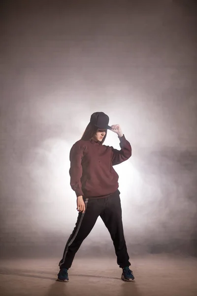 Giovane donna in abiti sportivi e cappello su uno sfondo scuro — Foto Stock