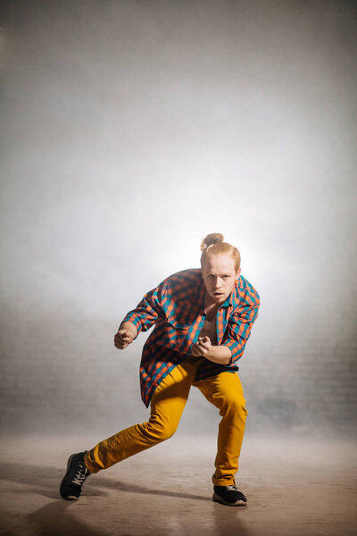 young male with checked shirt and yellow pantsbeckoning with the hands.