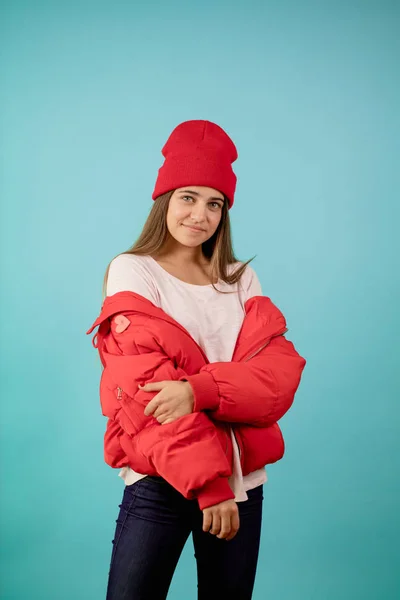 Mujer joven con chaqueta de jersey rojo sobre fondo azul aislado — Foto de Stock