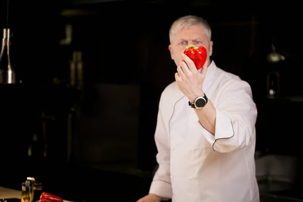 Cocinero jefe está sosteniendo pimiento rojo en su brazo — Foto de Stock