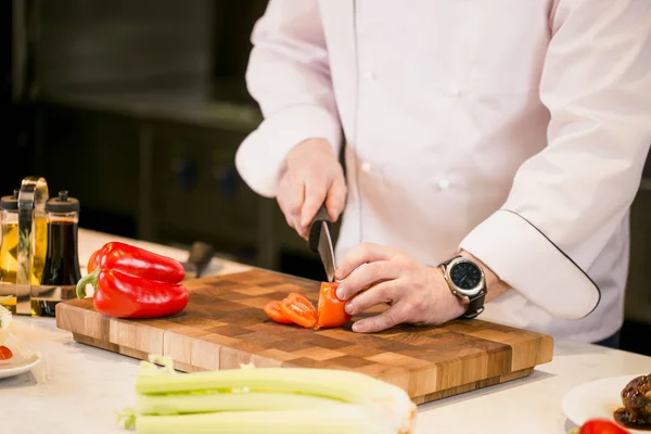 Closeup bijgesneden foto van man snijden tomaat op een snijplank in de keuken — Stockfoto