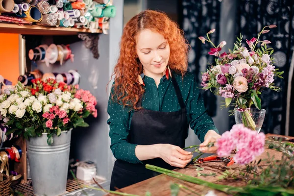 Vackra glad florist står bredvid hennes verktyg i en blomma verkstad — Stockfoto