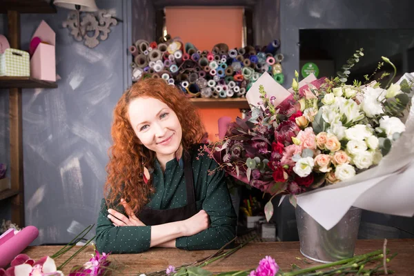 Verkäuferin mit Ingwerhaaren arbeitet mit Blumen im Blumenladen — Stockfoto