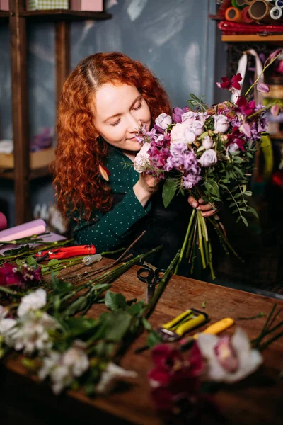 Tiro de hembra caucásica sentada a la mesa y respirando sabor a flores — Foto de Stock