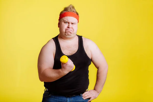 Hombre gordo tratar de levantar pequeño dambbell amarillo —  Fotos de Stock