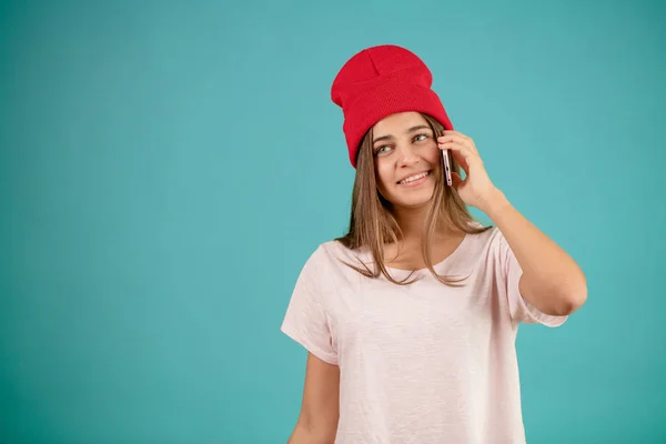 Donna attraente sorridente con lunghi capelli lisci e cappuccio rosso sta parlando al telefono — Foto Stock