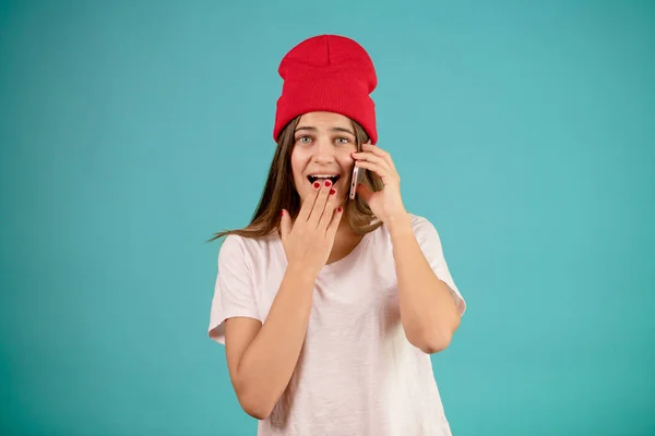 Милая женщина в повседневной одежде и красной кепке зевает во время разговора по телефону — стоковое фото