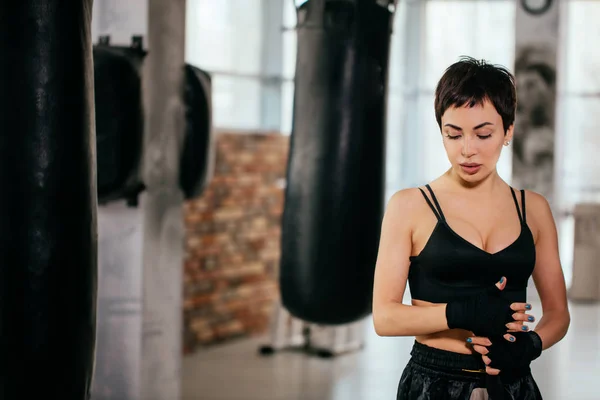 Jovem woan agradável em bandagens de boxe de pé com olhos fechados na sala de ginástica — Fotografia de Stock