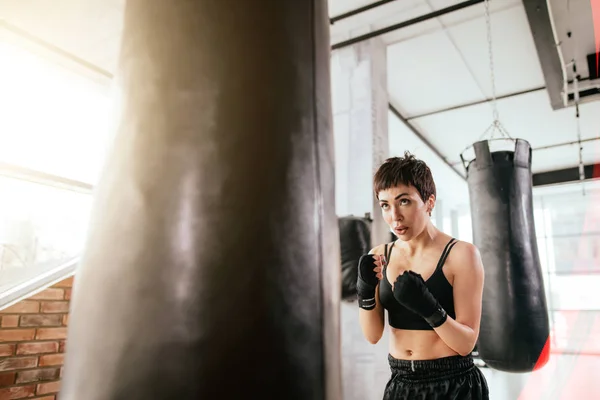 kung fu girl practising karate with boxing bag at sport hall