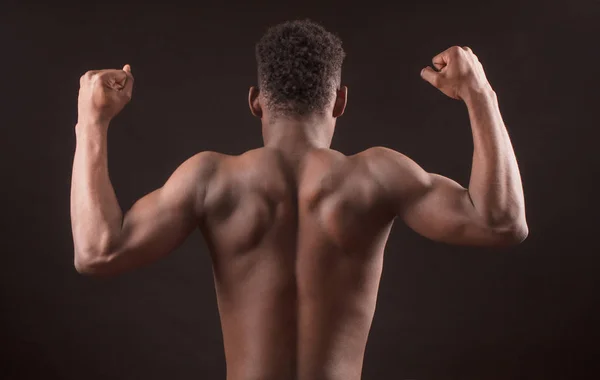 Afro sportsman flexar sina muskler isolerat på den svarta bakgrunden — Stockfoto