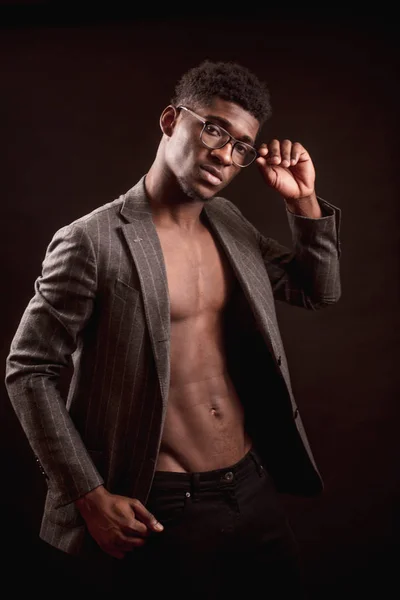 Delgado sexy afroamericano chico con gafas usando elegante abrigo y pantalones negros — Foto de Stock