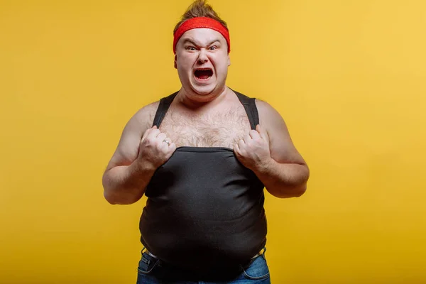 Hombre gordo con diadema roja y camisa negra grita sobre fondo oscuro —  Fotos de Stock