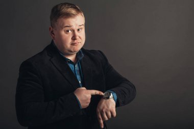 saatine bakıyor şaşırmış şişman beyaz adam.