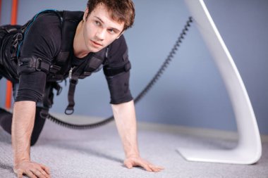 tahta egzersiz yaparak elektrik kas stimülasyonu elbiseli adam. EMS