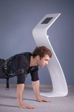 tahta egzersiz yaparak elektrik kas stimülasyonu elbiseli adam. EMS