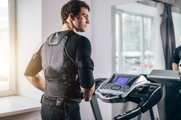 Man in black suit for ems training running on treadmill at gym — Stock Photo, Image