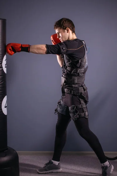 man in boxing gloves during training. boxer in suit of electric stimulation