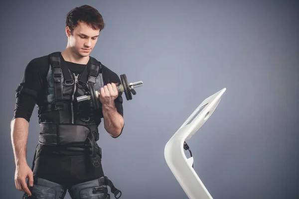 Uomo in giubbotto fitness biometrico sollevamento manubri durante l'allenamento in palestra ems — Foto Stock