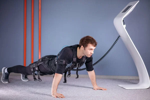 Homem em ternos de estimulação muscular elétrica fazendo exercício prancha. EMS — Fotografia de Stock