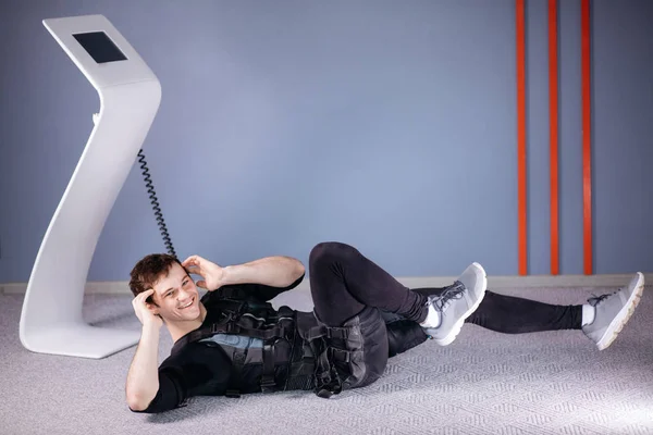 Atleta con traje ems haciendo ejercicios abdominales o sentados — Foto de Stock