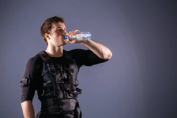 man wearing electro stimulation suit drink water after training