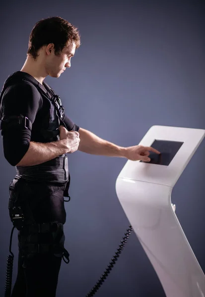 Atleta regulando a intensidade da máquina de estimulação eletromuscular ems — Fotografia de Stock