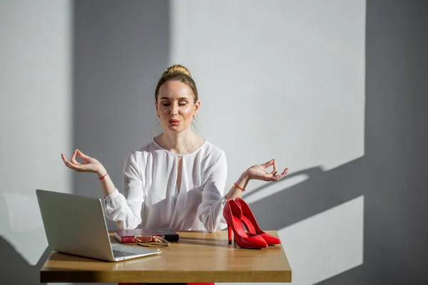 Привлекательная женщина медитация за столом с чашкой и ноутбуком — стоковое фото