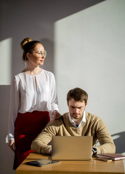 Mujer señalando al ordenador portátil con sonrisa y discutiendo algo con su compañero de trabajo — Foto de Stock