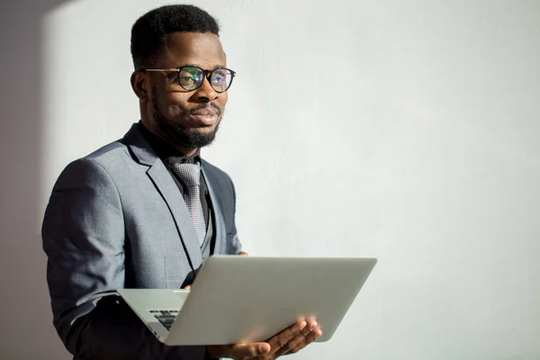 Colega de trabalho africano usando óculos e usando laptop no escritório — Fotografia de Stock