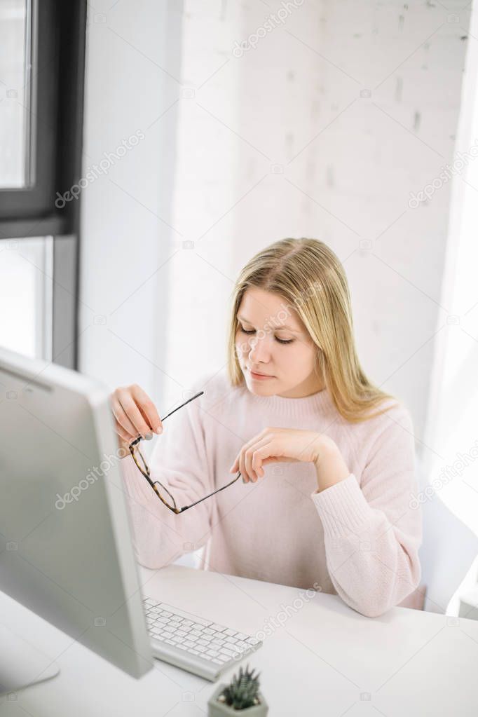 woman working in office, sitting at desk, using computer and looking on screen