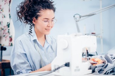 güzel seamstess önünde hareket bulanıklığı dikiş makinesi iş yerinde oturuyor