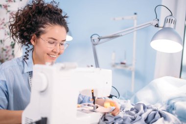 seamstess dalgalı saçlı yakışıklı ve gösteren usta-sınıfı dikiş üzerinde gözlük