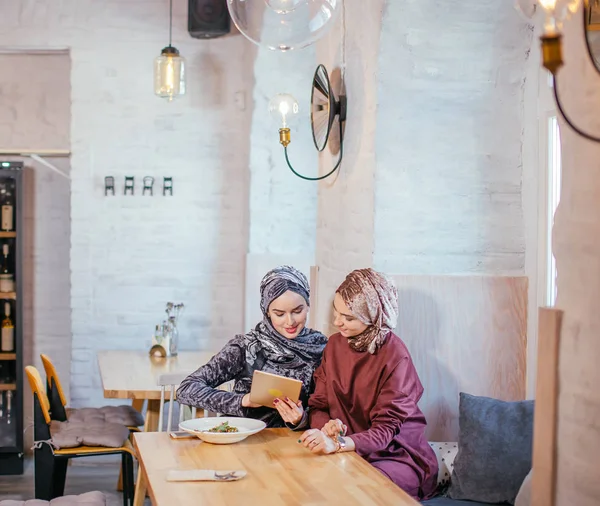 Duas mulheres muçulmanas no café, loja on-line usando tablet eletrônico — Fotografia de Stock