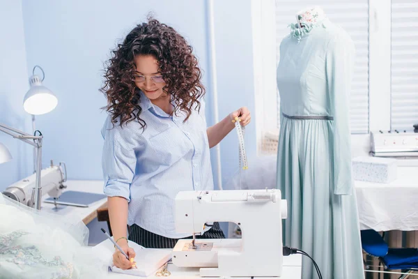 Dressmake segurando fita métrica e lápis para escrever medição na oficina — Fotografia de Stock