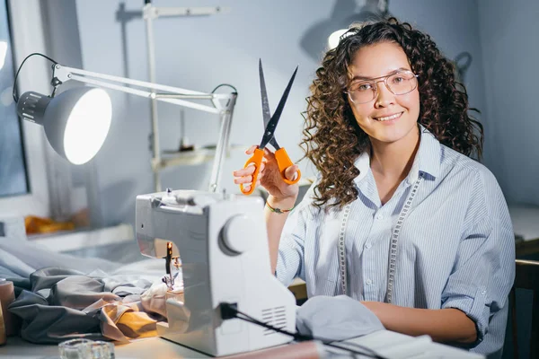 Gelukkige naaister houdt oranje schaar om te beginnen met naaien — Stockfoto