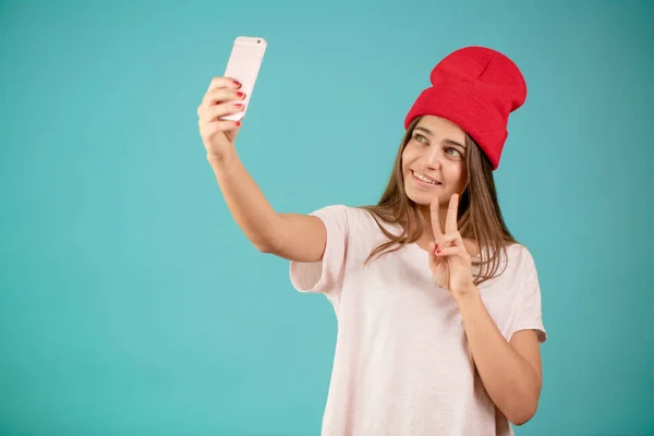 Joven chica morena sonriente haciendo selfie sobre el fondo azul aislado — Foto de Stock