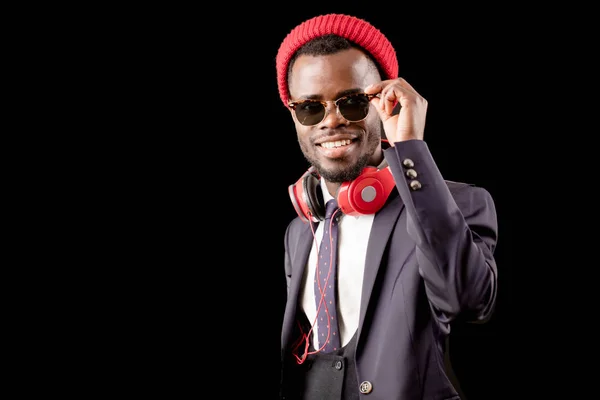 Cantante con barba con un atuendo elegante en gafas de sol, auriculares rojos y gorra — Foto de Stock