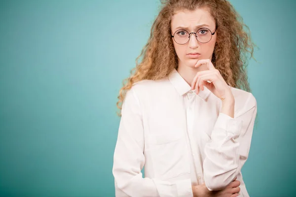 Giovane donna d'affari pensierosa con le sopracciglia sollevate sta toccando il mento — Foto Stock