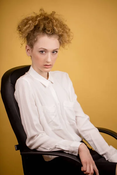 Secretária vestindo seu cabelo sentado e olhando para a câmera enquanto trabalhava — Fotografia de Stock