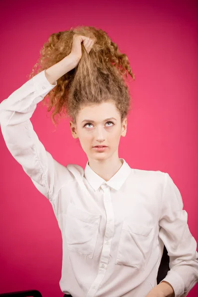 Ung kvinna försöker samla sin ostyrigt hår — Stockfoto