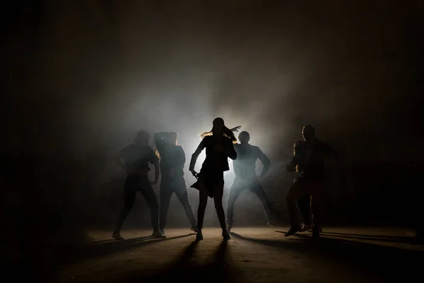 Um grupo de dançarinos de rua realizando diferentes movimentos na rua escura — Fotografia de Stock